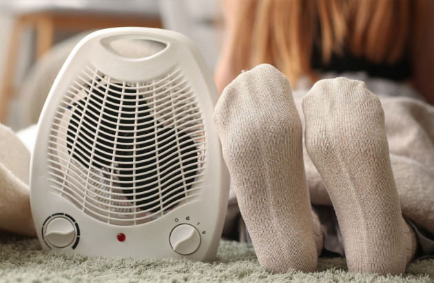 Femme qui met ses pieds à côté d'un radiateur soufflant