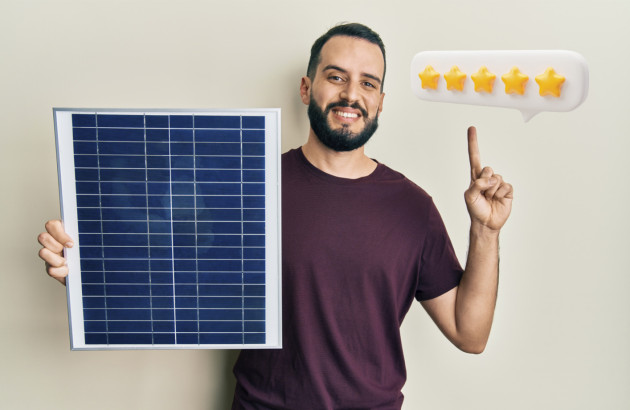 Homme heureux qui met la note de 5 étoiles en tenant un panneau solaire dans la main