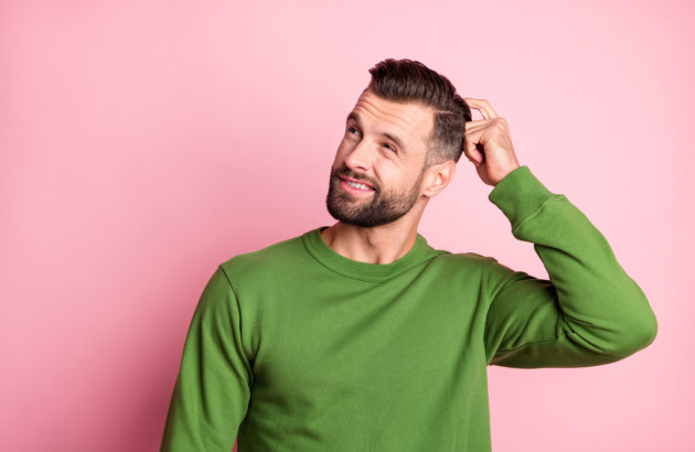 Homme qui se gratte la tête devant un fond vert