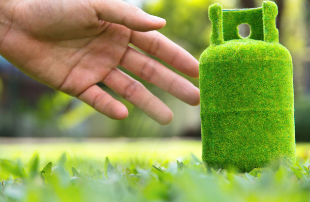 main qui attrape une bouteille de biogaz avec une texture d'herbe