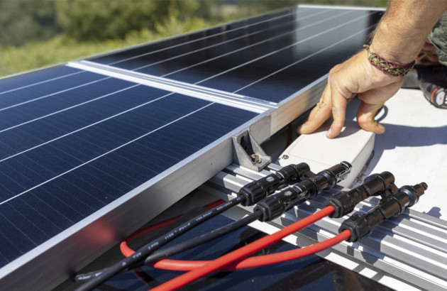 personne qui s'occupe de câbler des panneaux solaires entre eux