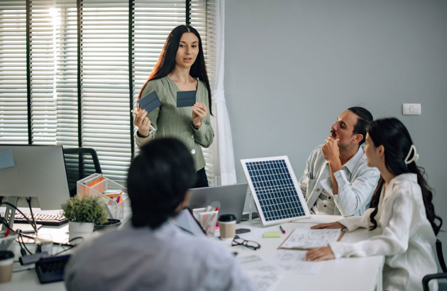 Femme qui présente des panneaux solaires à son équipe de travail