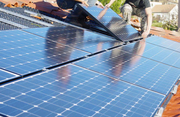 Equipe de travailleurs qui installe des panneaux solaires sur un toit de maison