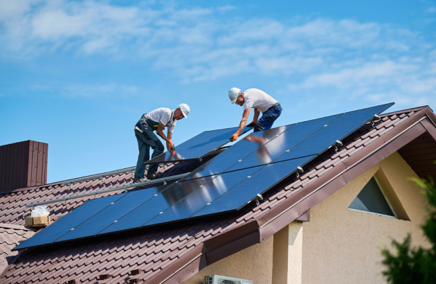 Deux artisans qui installent des panneaux solaires sur le toit d'une maison