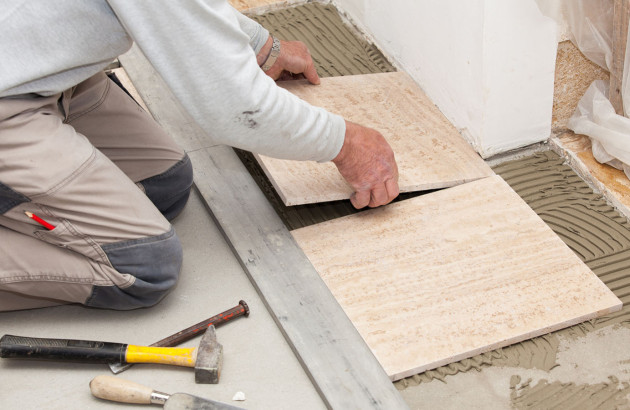 Artisan qui pose des carreaux de carrelage sur le sol