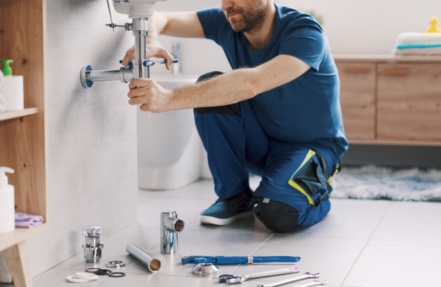 Artisan en train d'installer un tuyau d'évacuation des eaux pour un lavabo