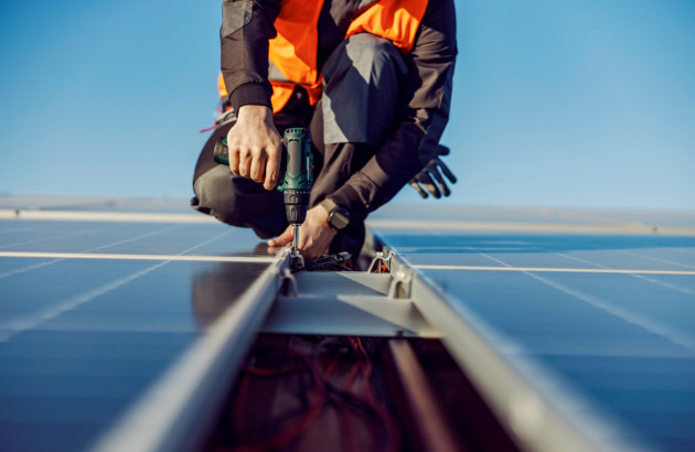 Artisan qui fixe des panneaux solaires