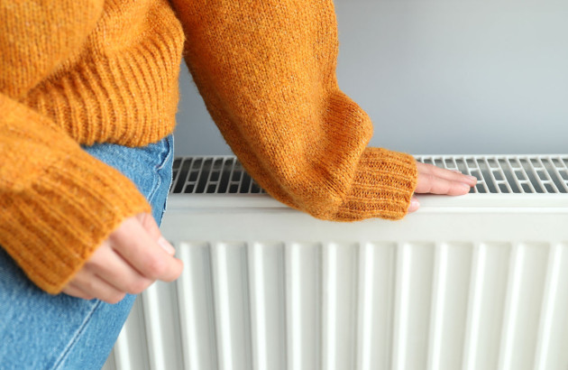 Femme qui pose sa main sur un radiateur pour en ressentir la chaleur