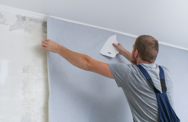 Homme en train de poser du papier peint dans le mur