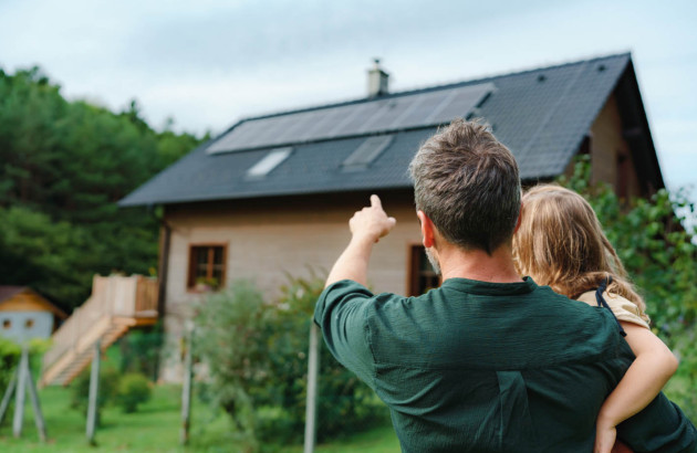 Père montrant à sa fille leur maison équipée de panneaux solaires