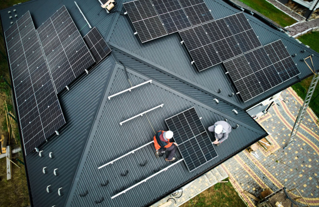 Professionnels accrochant des panneaux solaires sur les toits