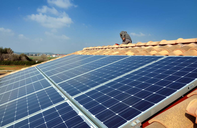 Panneaux solaires installés sur un rail posé sur un toit en tuiles