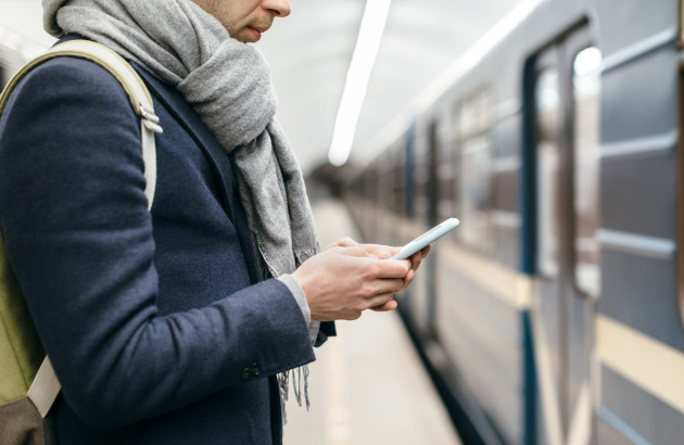 Personne sur son téléphone devant une rame de métro