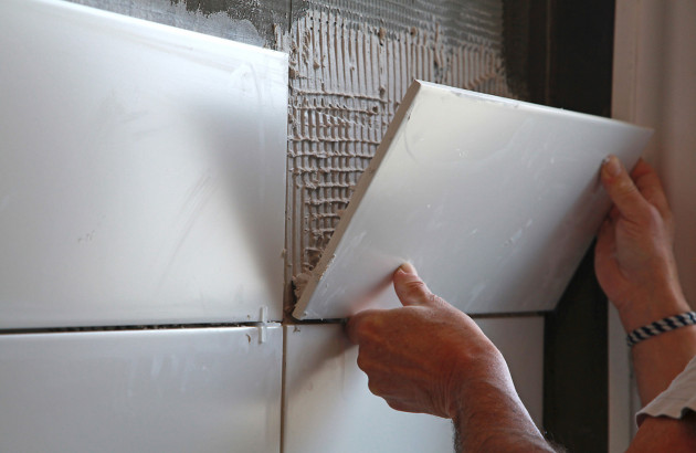 Homme qui pose du carrelage sur un mur