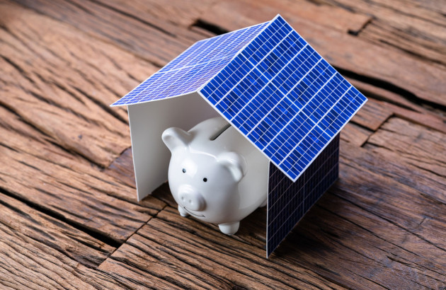 Tirelire cochon sous une maison de panneaux solaires, symbole de prix d'une installation solaire