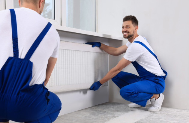 Artisans qui installent un radiateur dans une maison