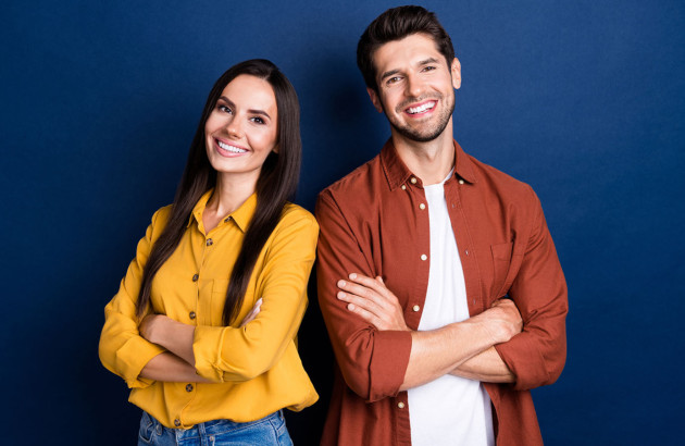 Deux personnes qui sourient devant un fond bleu