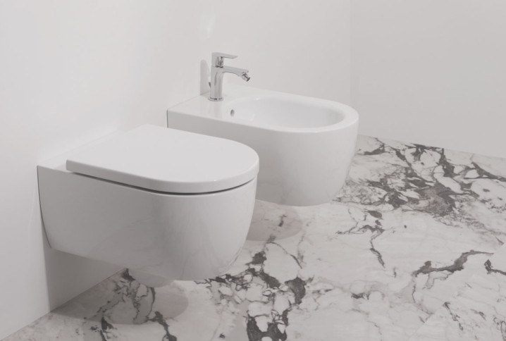 WC et bidet côte à côté dans une pièce avec du carrelage effet marbre