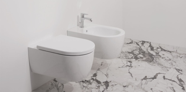 WC et bidet côte à côté dans une pièce avec du carrelage effet marbre